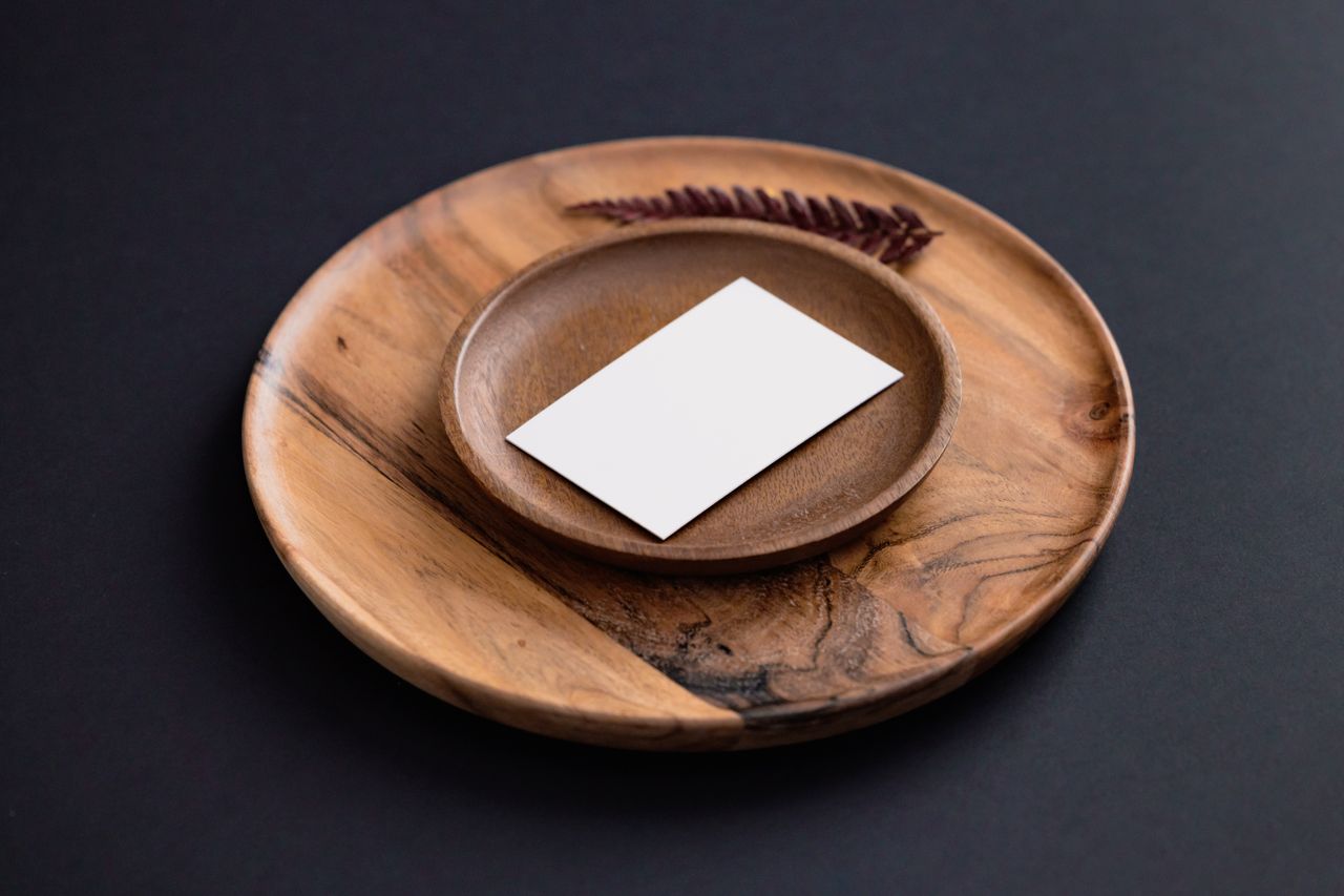 A minimalist setup featuring a wooden plate and blank card for branding or presentations.