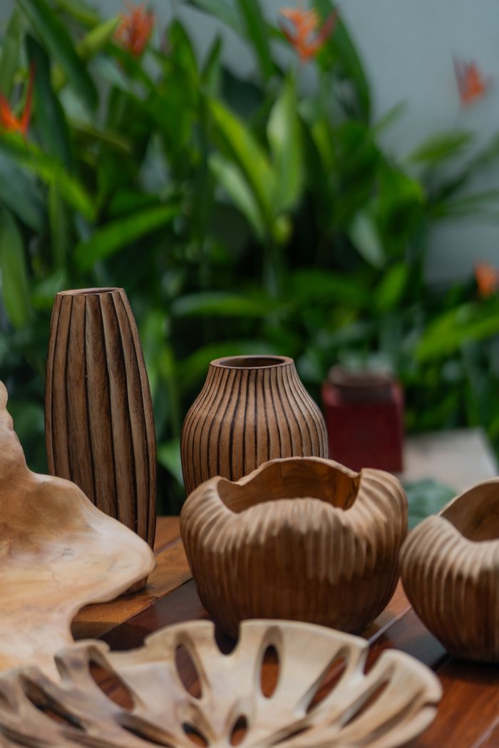 Elegant handmade wooden vases displayed against lush green foliage, showcasing natural craftsmanship.