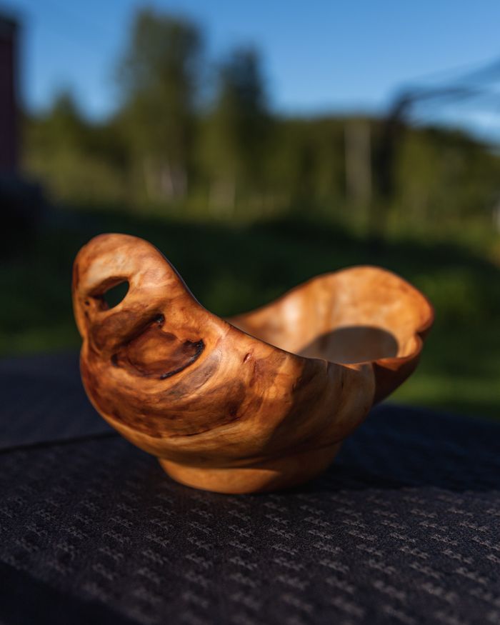 A unique handmade wooden bowl showcasing artistic design and craftsmanship in a natural outdoor setting.
