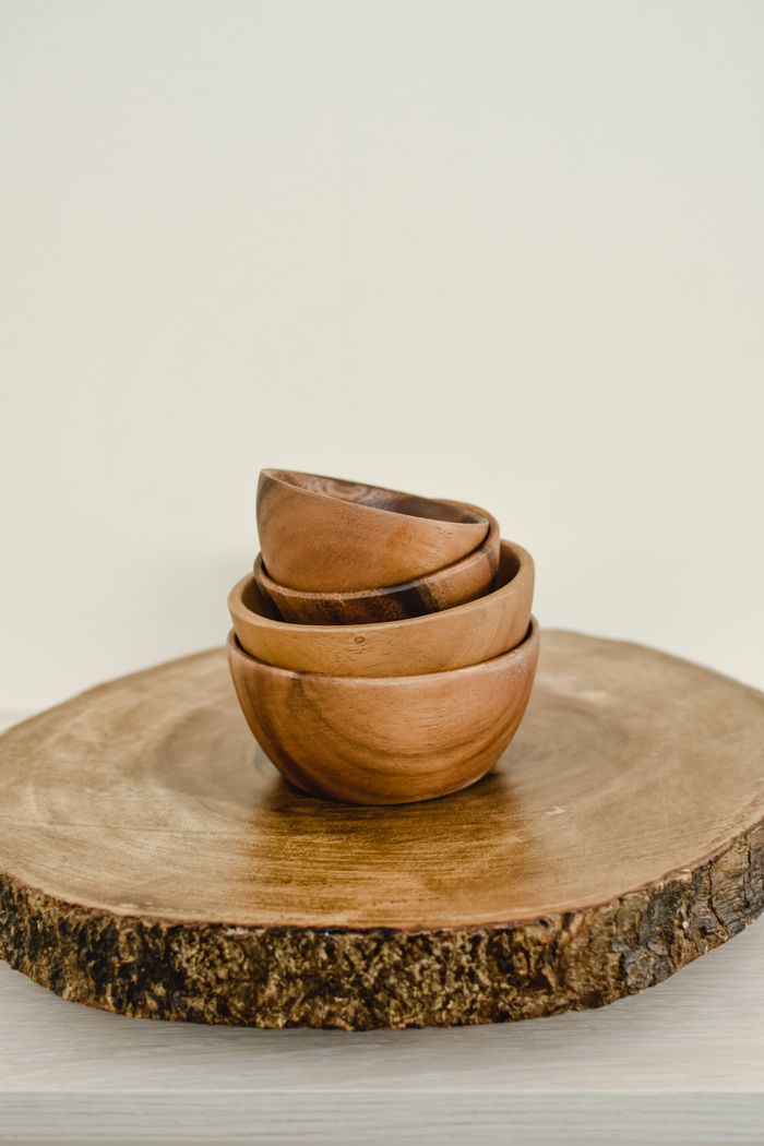 Minimalist still life of wooden bowls stacked on a slice of wood, emphasizing Scandinavian design.