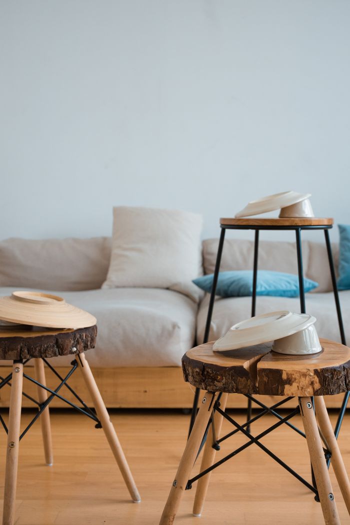 A modern living room featuring sleek wooden stools and a cozy sofa, highlighting minimalist design.